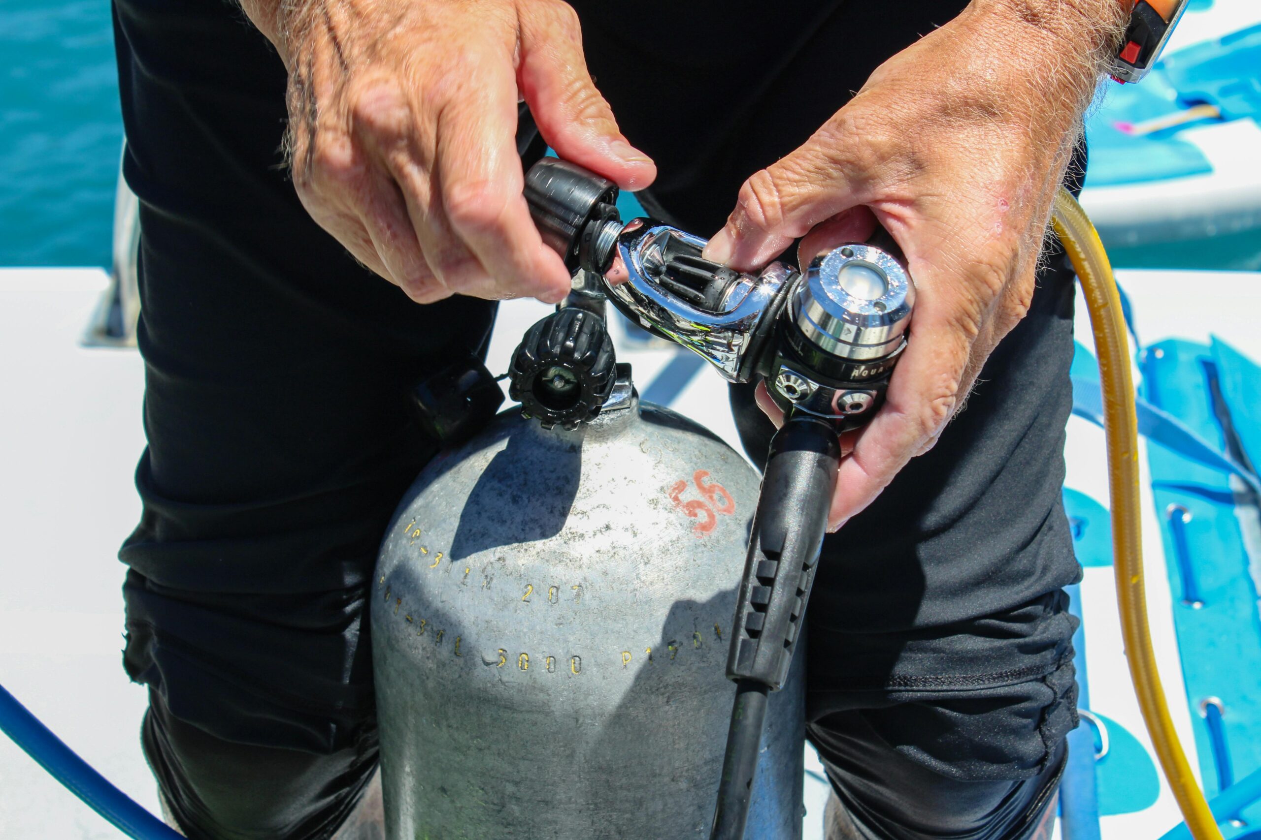 Technical diving courses in Bali with instructor attaching a regulator to a scuba cylinder.